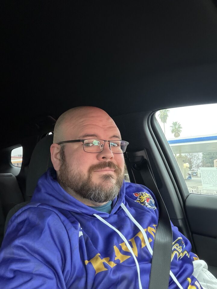 Sly Panorama car selfie wearing a Baltimore Ravens hoodie at a daytime gas station.